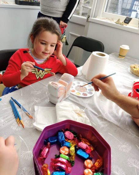 a young girl painting her butterfly money box