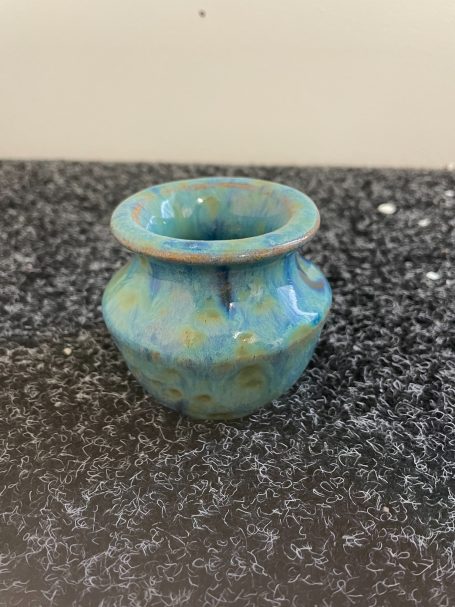 a hand thrown piece from their pottery course using a green blue yellow speckled glaze