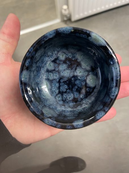 Handmade piece using a blue and black speckled glaze on their pottery course