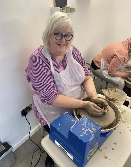 a lady throwing her pottery on the potters wheel